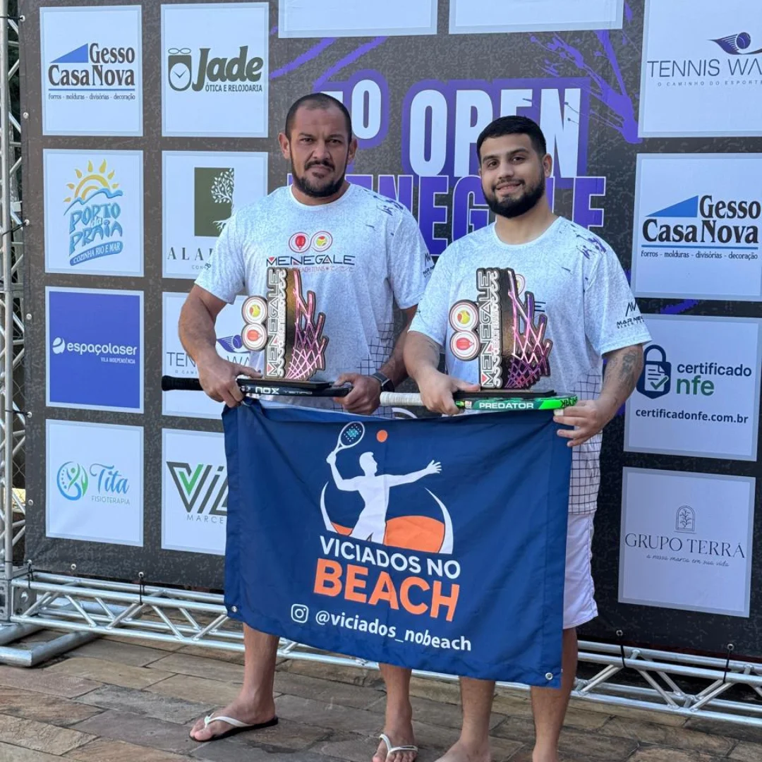 Dois atletas seguram a bandeira VNB com troféus
