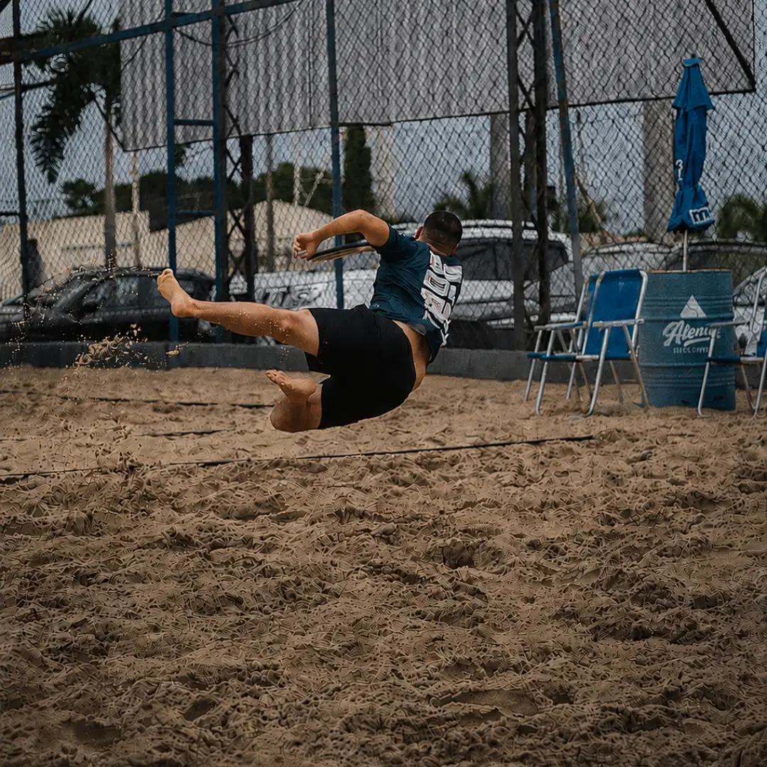 Atleta se lança na areia para alcançar a bola