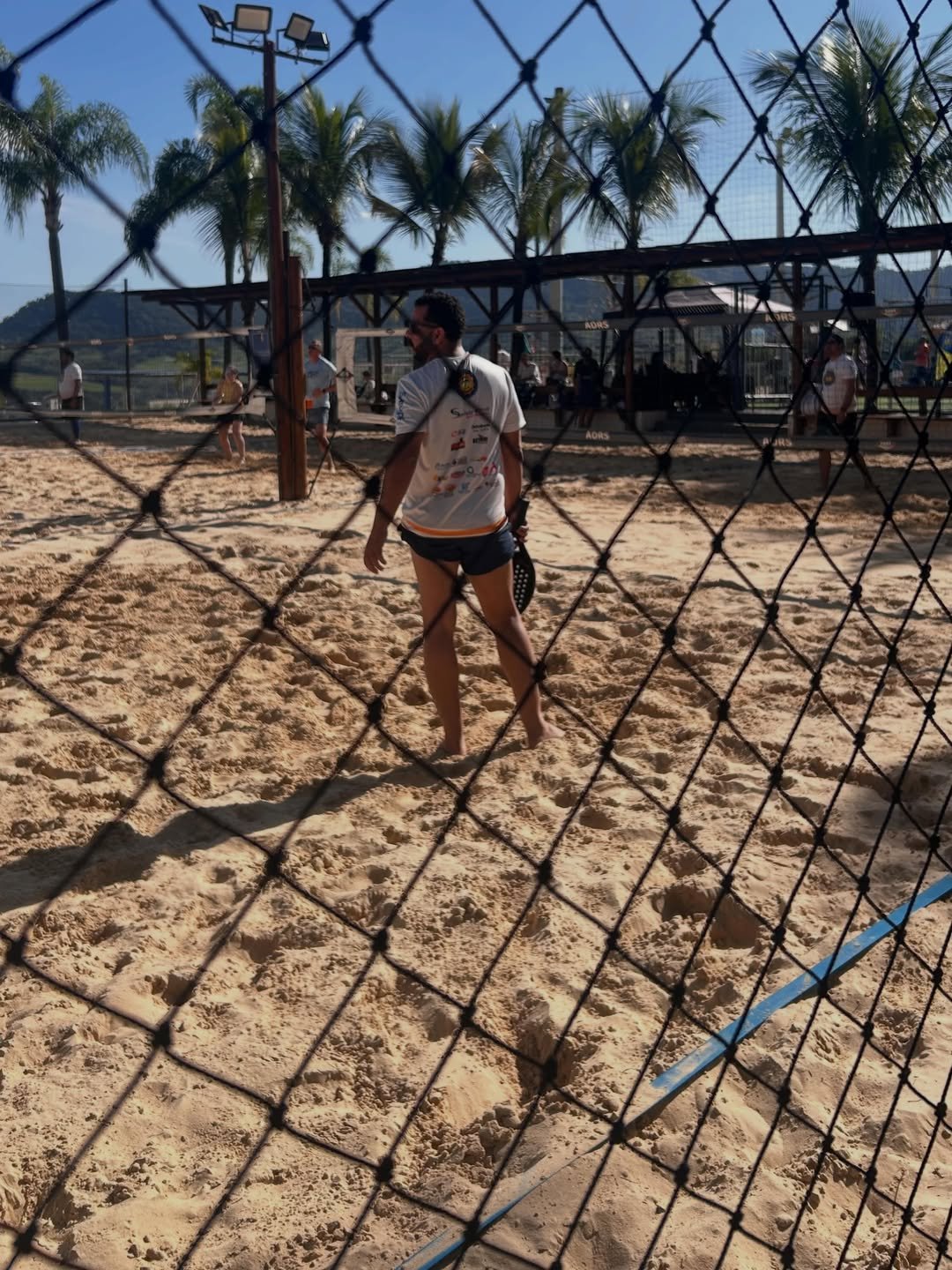 Atletas em quadra vistos através da rede